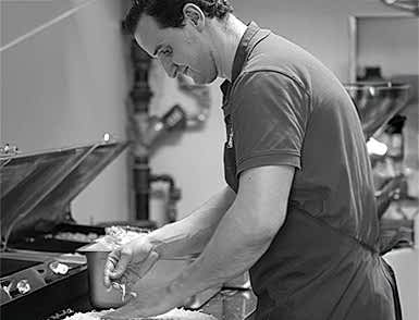 A dedicated chef at Delish Pizza prepares a fresh pizza, showing culinary passion and craftsmanship.